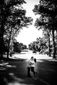 a man and woman kissing on a road with trees